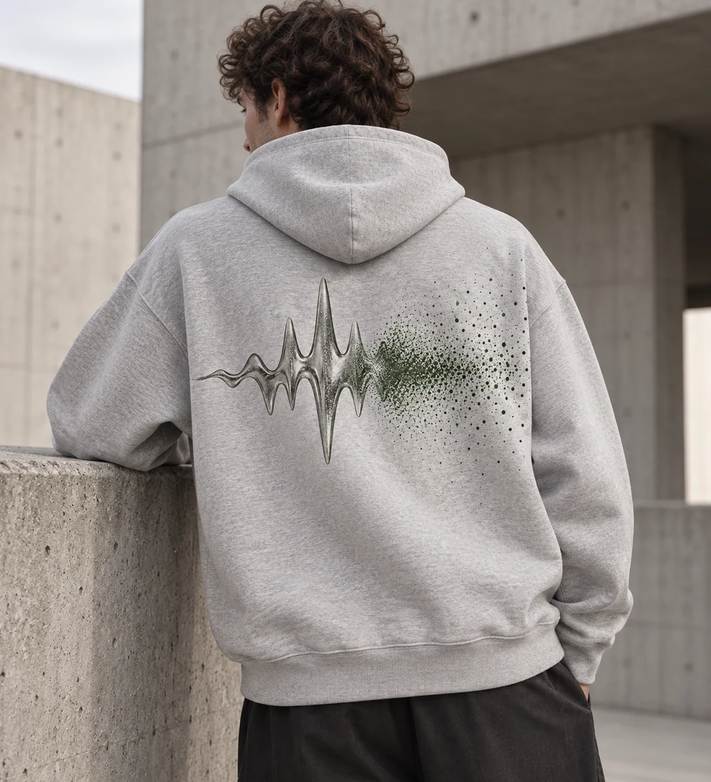 Adult model wearing an ash-grey SIGNAL oversized hoodie with a silver waveform and green grain back print